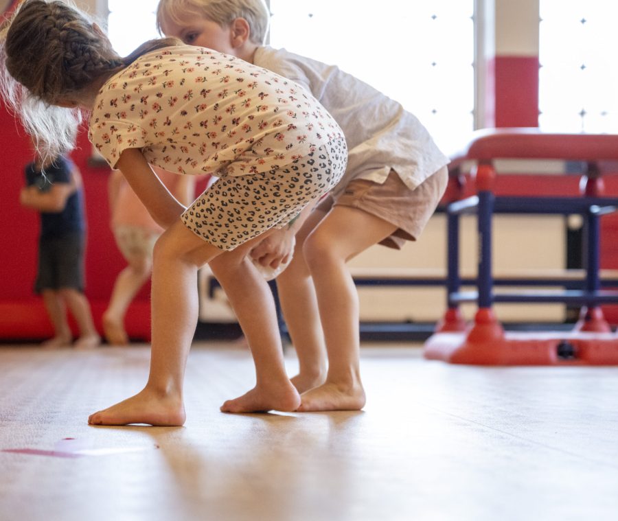 Two young children engaged in a playful headtohead standoff in a colorful playroom.